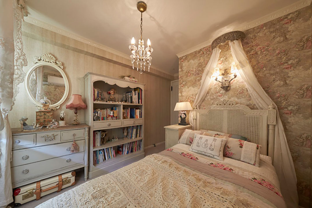 田園をモチーフとしたトワル・ド・ジュイの壁紙がアンティークのベッドを引き立てる来客用寝室