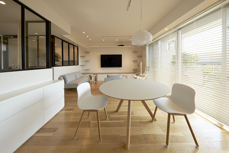 白いダイニングテーブルと椅子、木製の床、テレビ付きリビングの画像