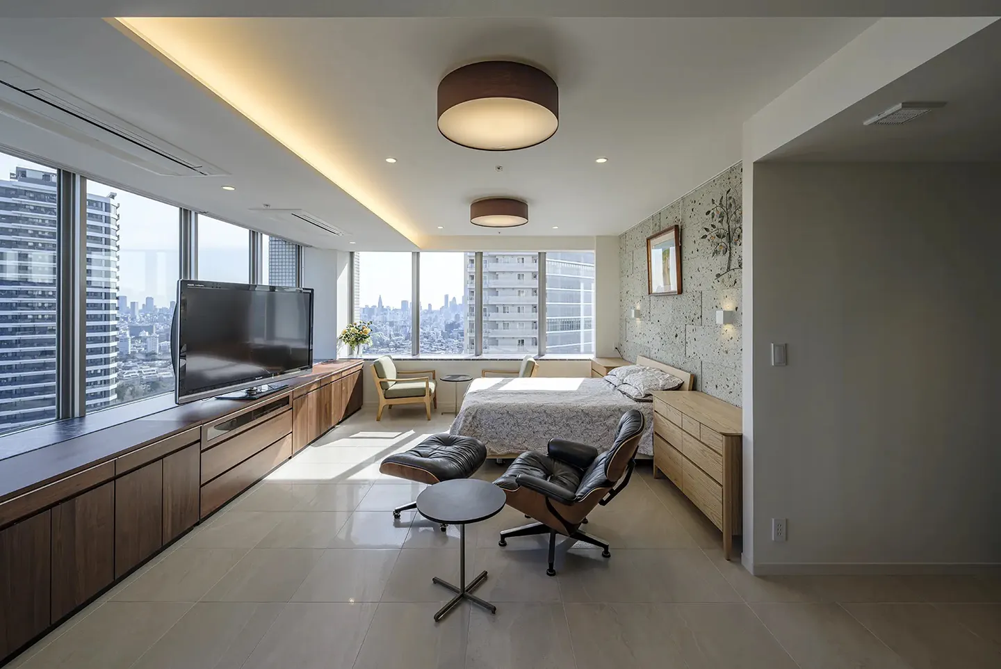 窓の外に都会の眺望が広がるリビング兼ベッドルーム